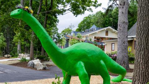 very large statue of a bright green dinosaur, outdoors