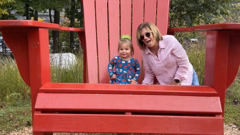 a woman and young child sit on a giant red Adirondeck chair